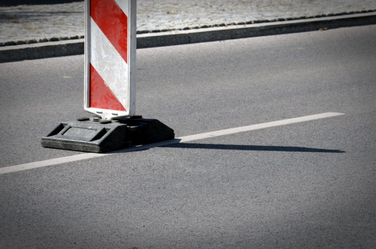 Biało-czerwony pachołek na drodze informujący o utrudnieniach w ruchu.