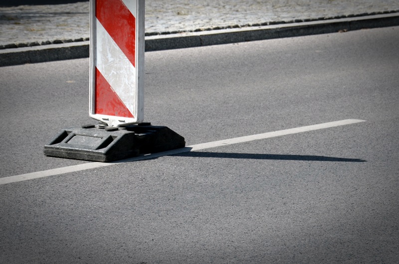 Biało-czerwony pachołek na drodze informujący o utrudnieniach w ruchu.