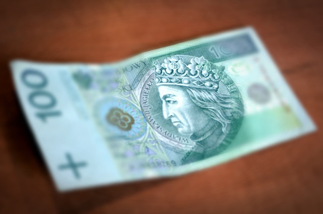 Banknot stuzłotowy z wizerunkiem króla Władysława II Jagiełły. W tle po jego obu stronach znajdują się stylizowane elementy ornamentyki gotyckiej.