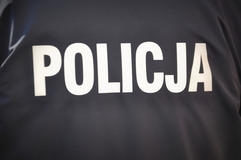 Napis policja na czarnej kurtce funkcjonariusza policji