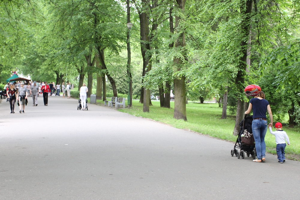 Parkową alejką spacerują ludzie