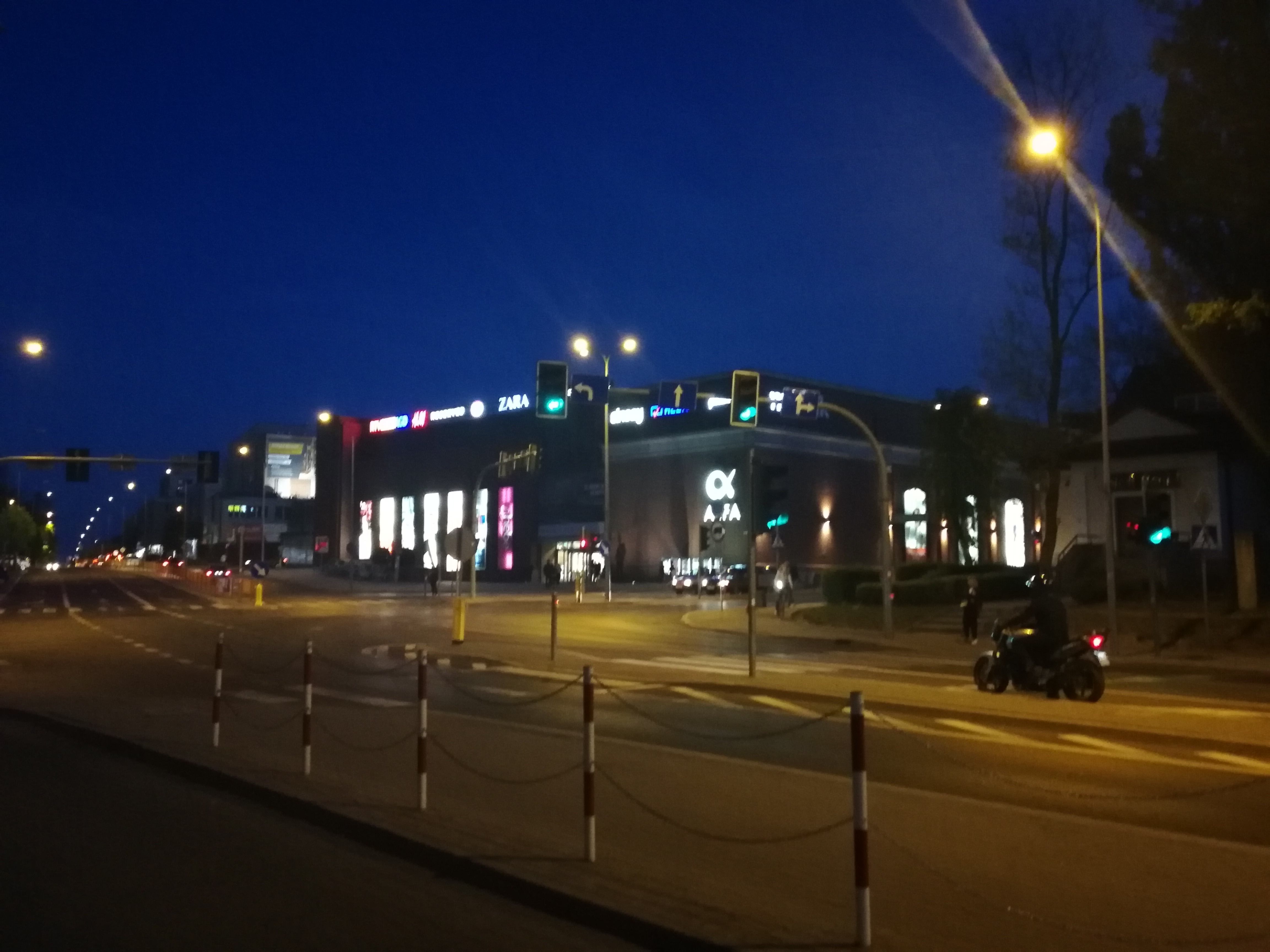 Noc, miasto, ulica, w oddali widać światła i zarys galerii handlowej