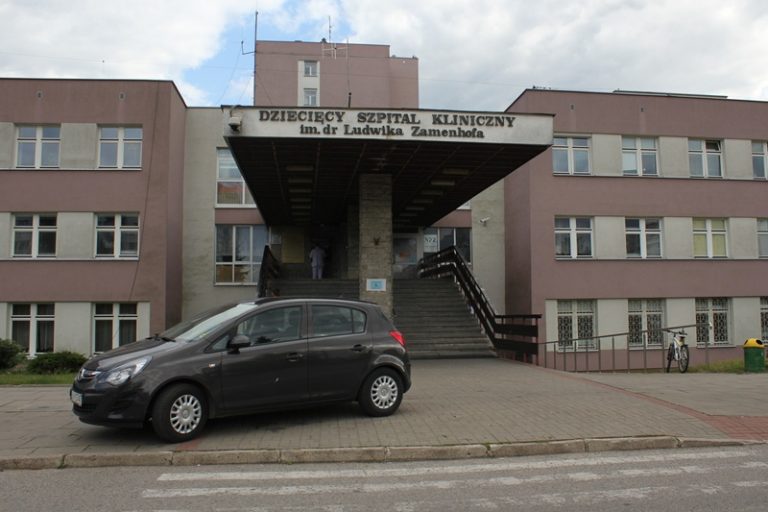 Wejście główne do Uniwersyteckiego Dziecięcego Szpitala Klinicznego im. dr. Ludwika Zamenhofa w Białymstoku, przed budynkiem zaparkowany samochód