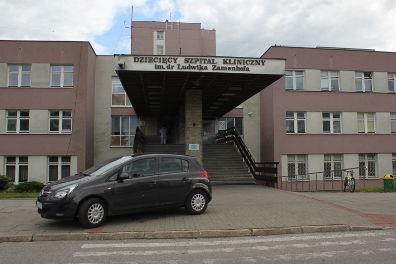 Wejście główne do Uniwersyteckiego Dziecięcego Szpitala Klinicznego im. dr. Ludwika Zamenhofa w Białymstoku, przed budynkiem zaparkowany samochód