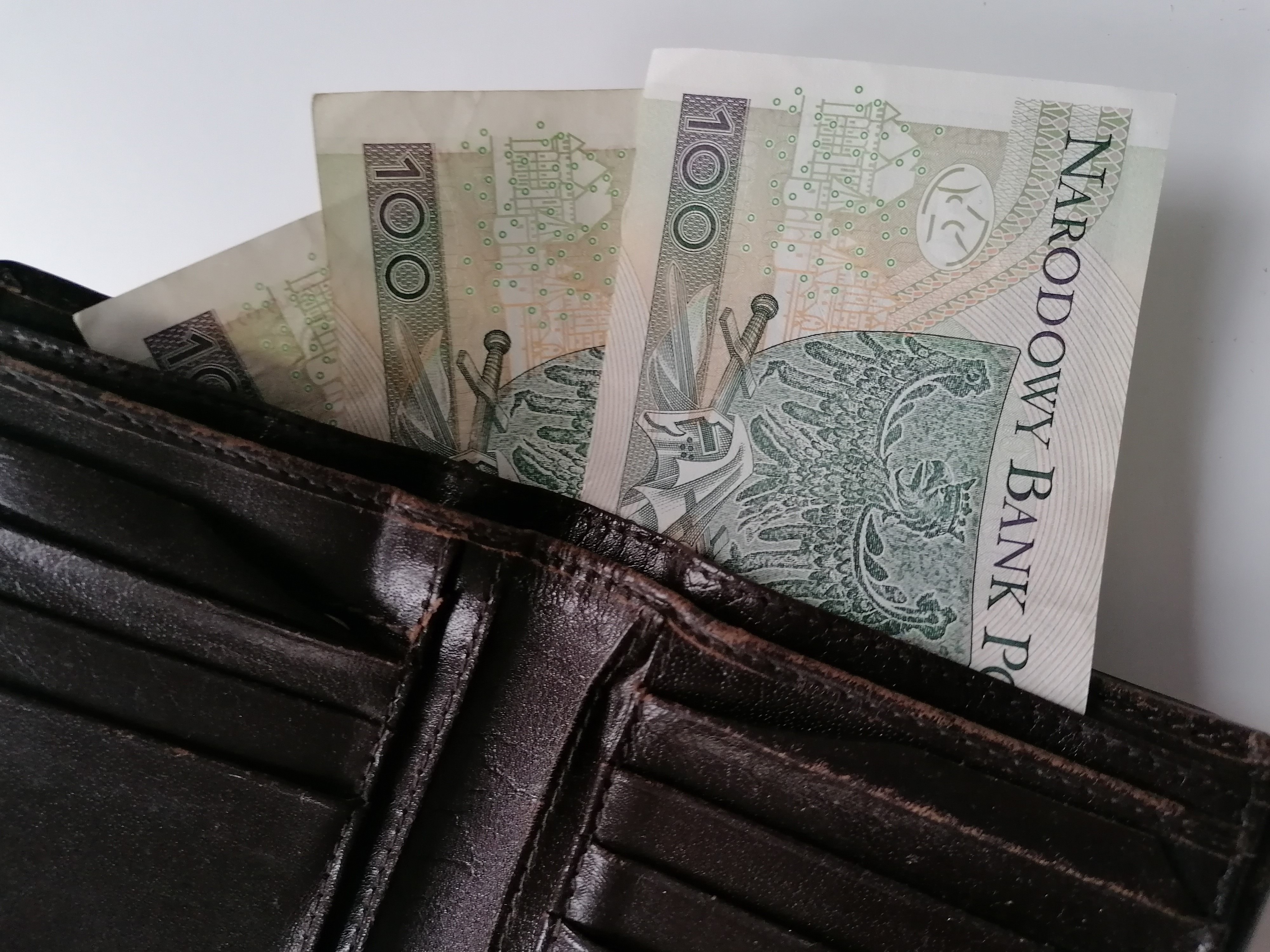 Trzy stuzłotowe banknoty wystają z portfela