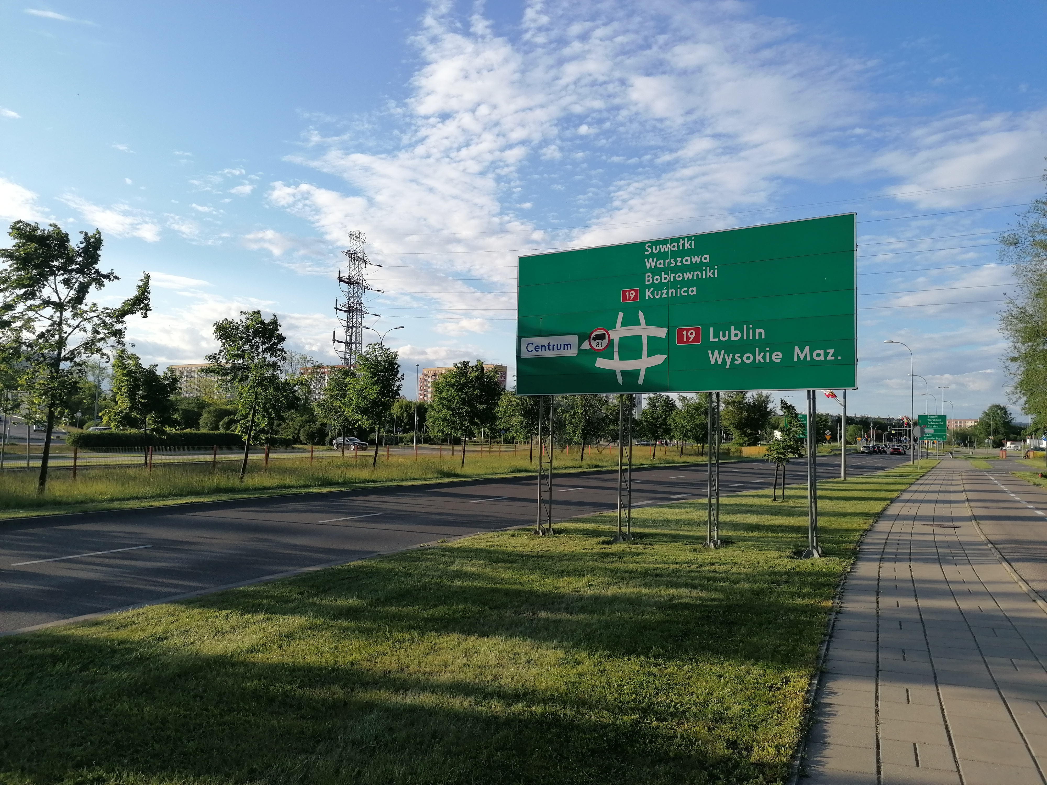 Pas zieleni a nim tablica drogowa