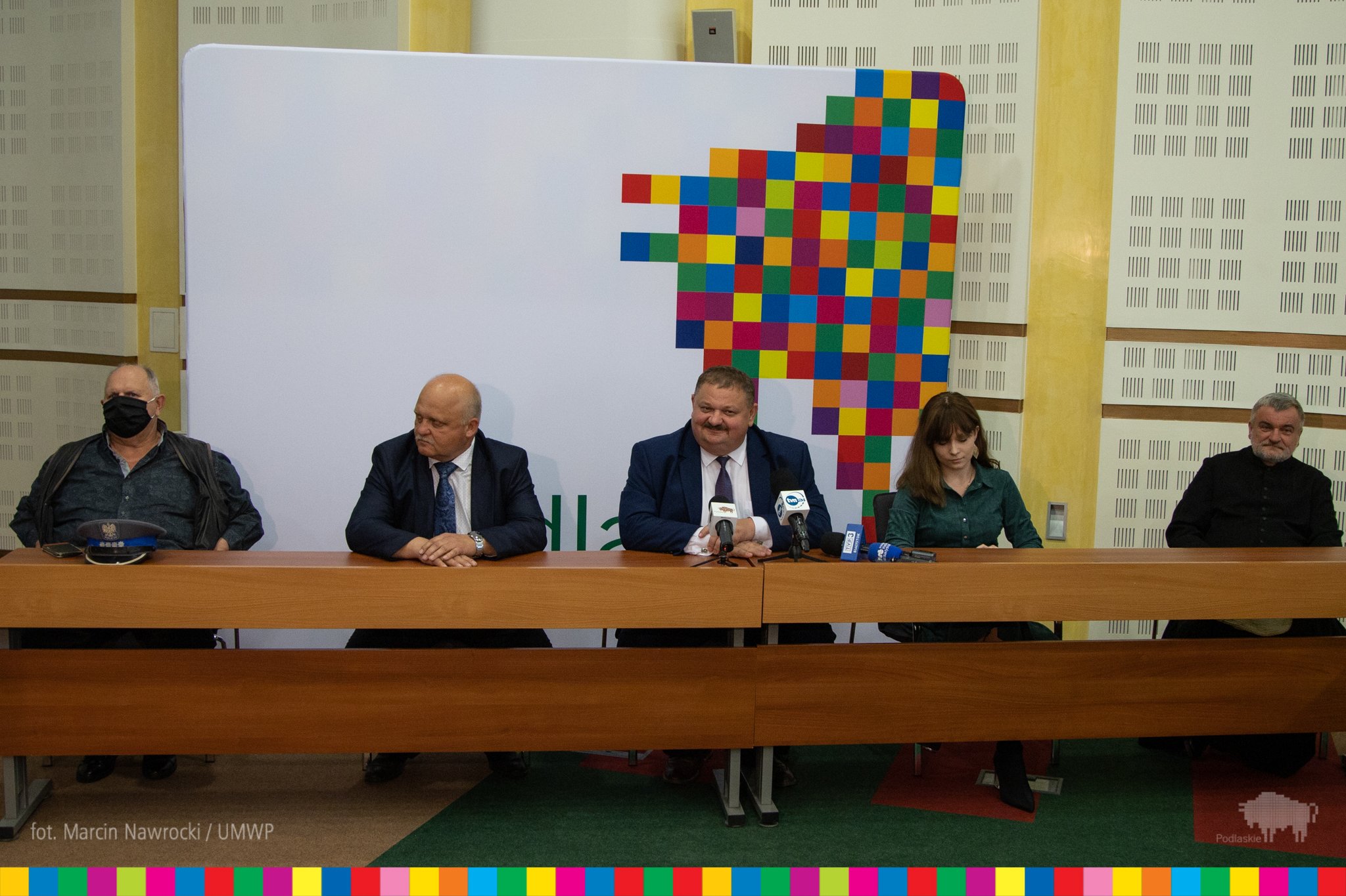 Konferencja prasowa w Urzędzie Marszałkowskim. Przy stole siedzą białostoccy aktorzy oraz wicemarszałek Podlaskiego. Za nimi widać pikselowego żubra