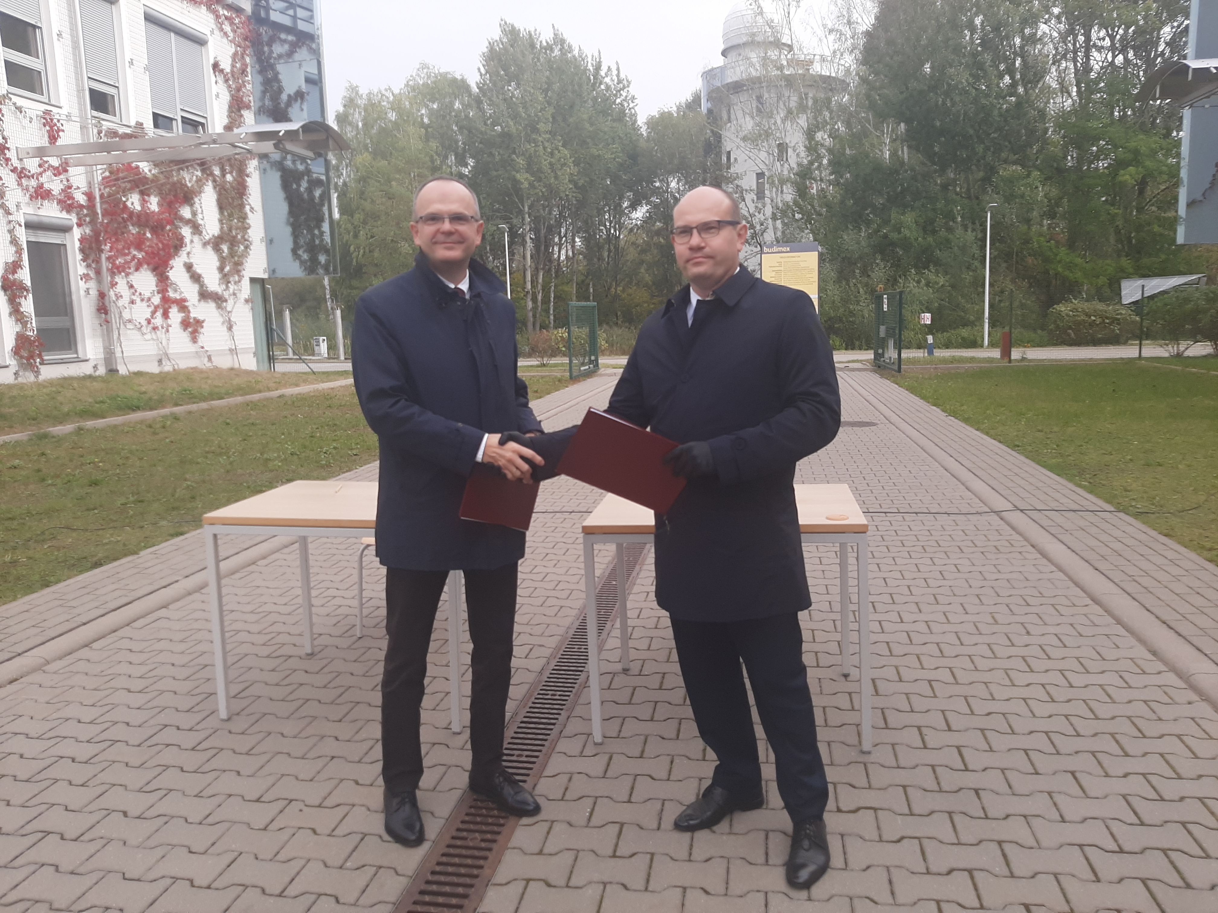 Rektor Uniwersytetu w Białymstoku i marszałek województwa podlaskiego wymieniają się podpisanymi umowami na dofinansowanie wyposażenia obserwatorium. Za nimi widoczna jest kopuła obserwatorium z planetarium