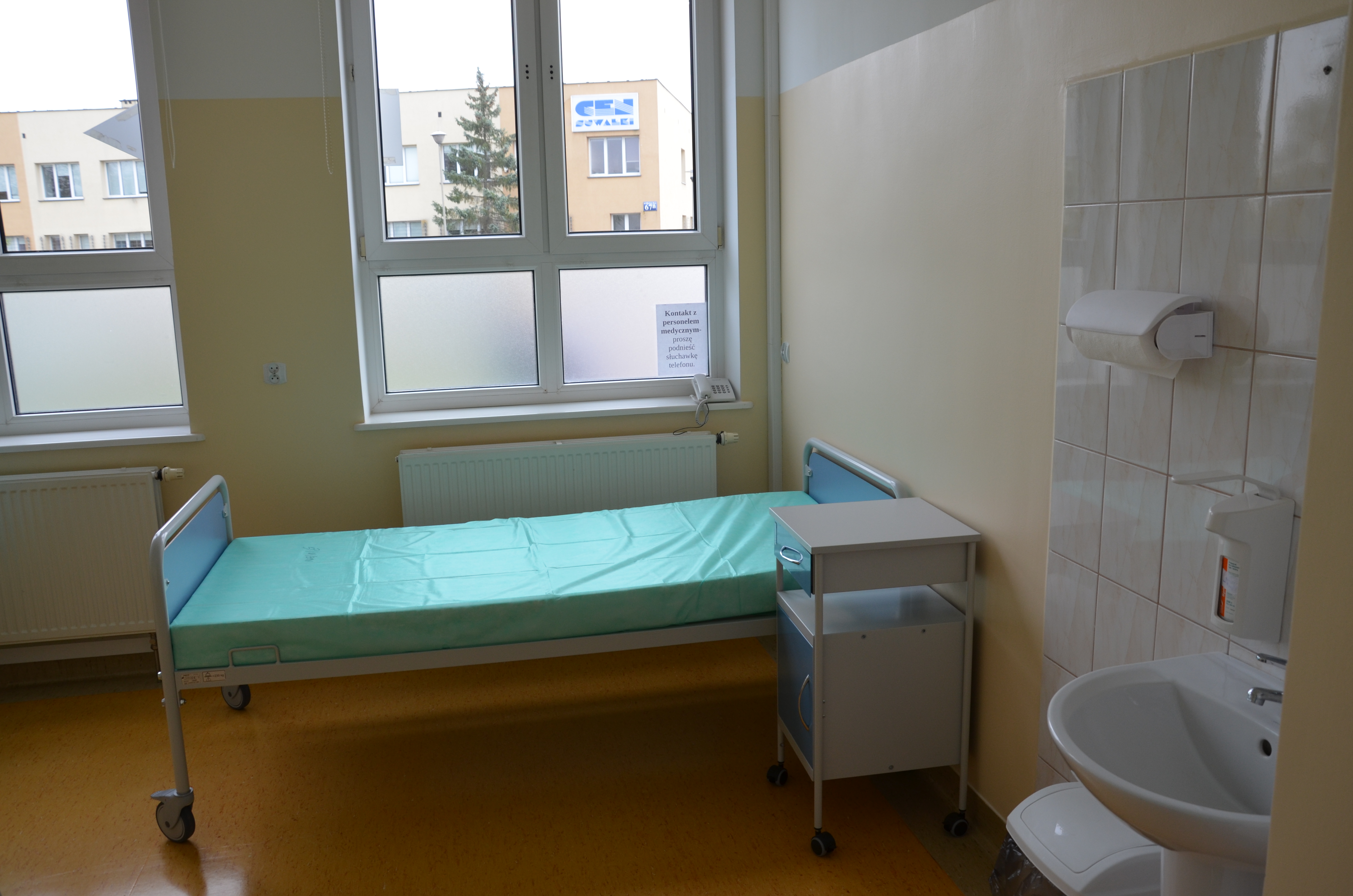 Sala szpitalna, a w niej łóżko dla chorego.