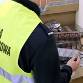 Funkcjonariusz KAS trzyma w ręku paczki papierosów