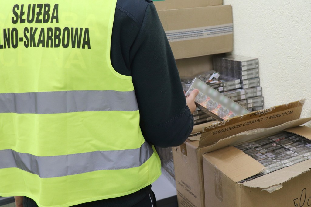 Funkcjonariusz KAS trzyma w ręku paczki papierosów