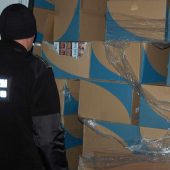 Pogranicznik stoi przy kartonach z nielegalnymi papierosami