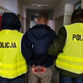 Policjanci trzymają skutego kajdankami mężczyznę