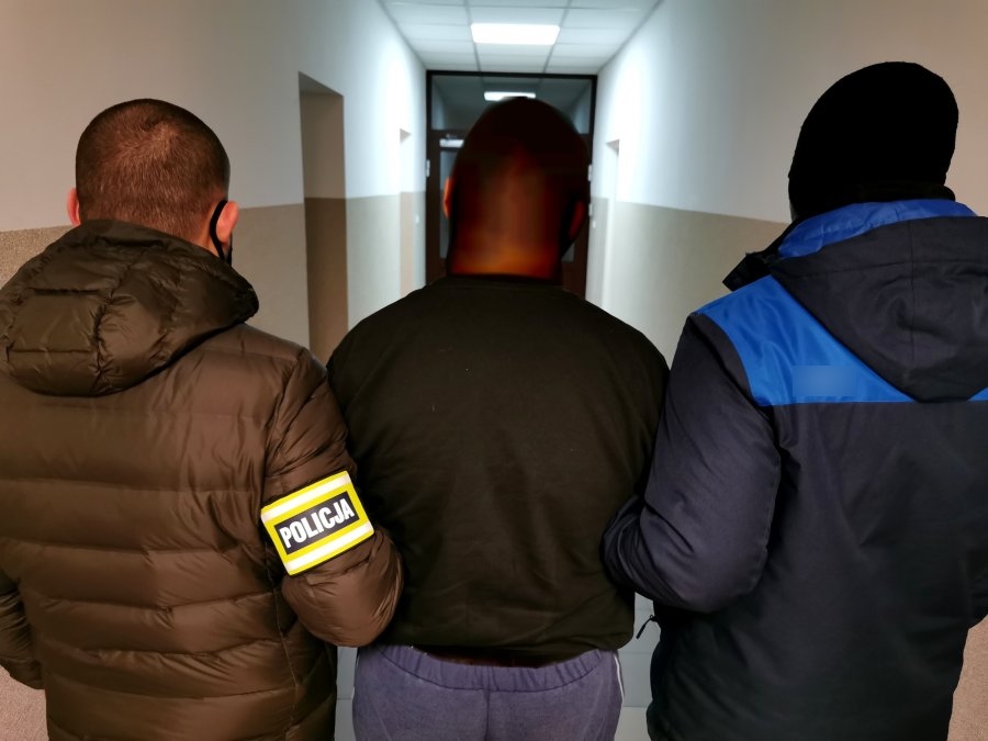 Policjanci trzymają skutego kajdankami mężczyznę