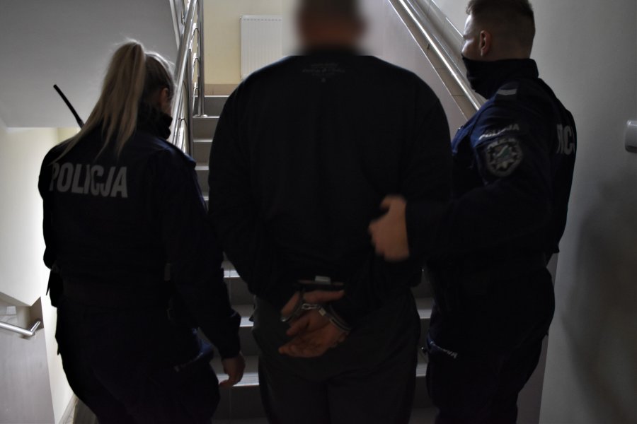 Dwoje policjantów prowadzi skutego kajdankami mężczyznę