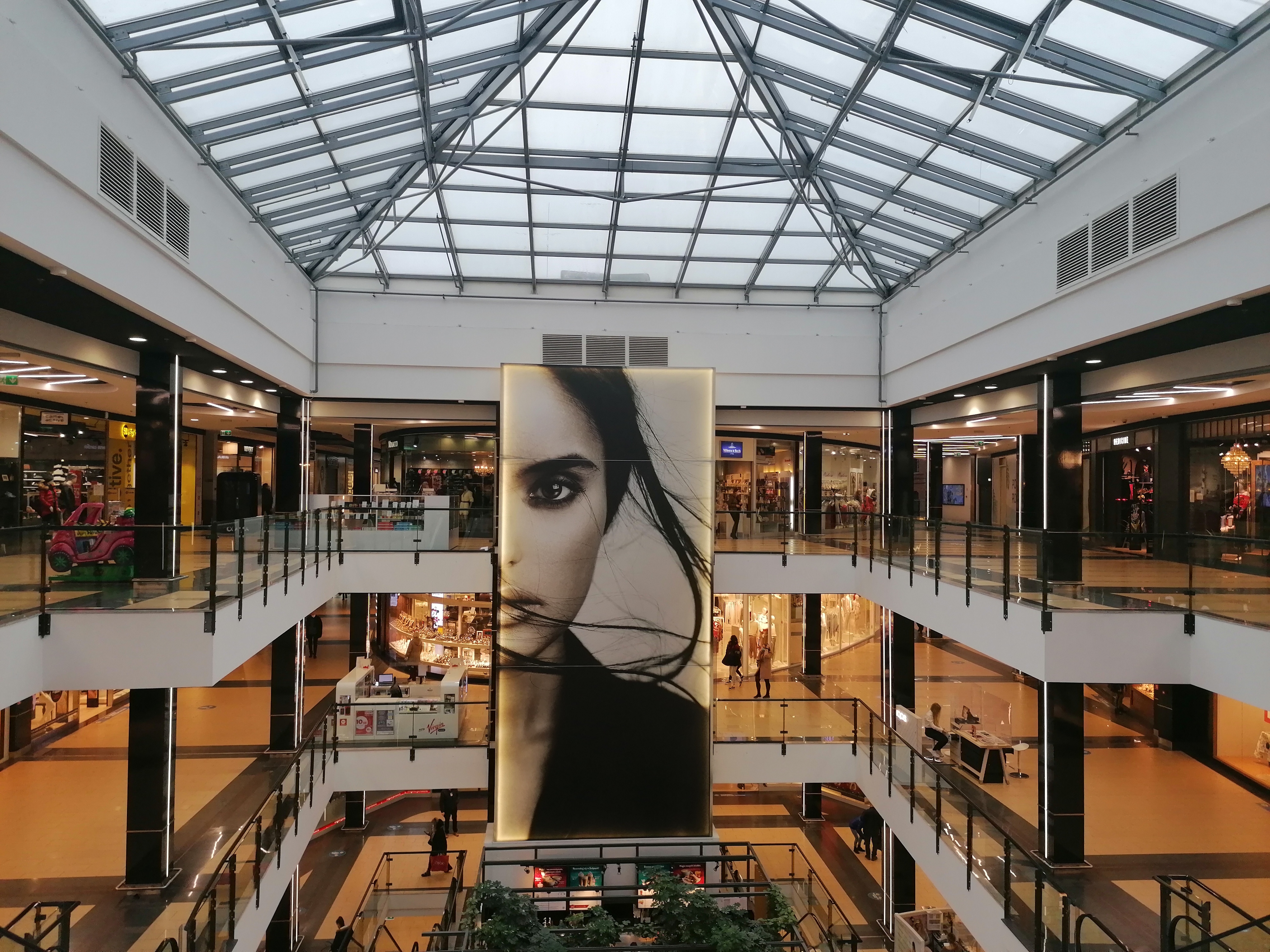 Wnętrze galerii handlowej, w tle widać ludzi robiących zakupy