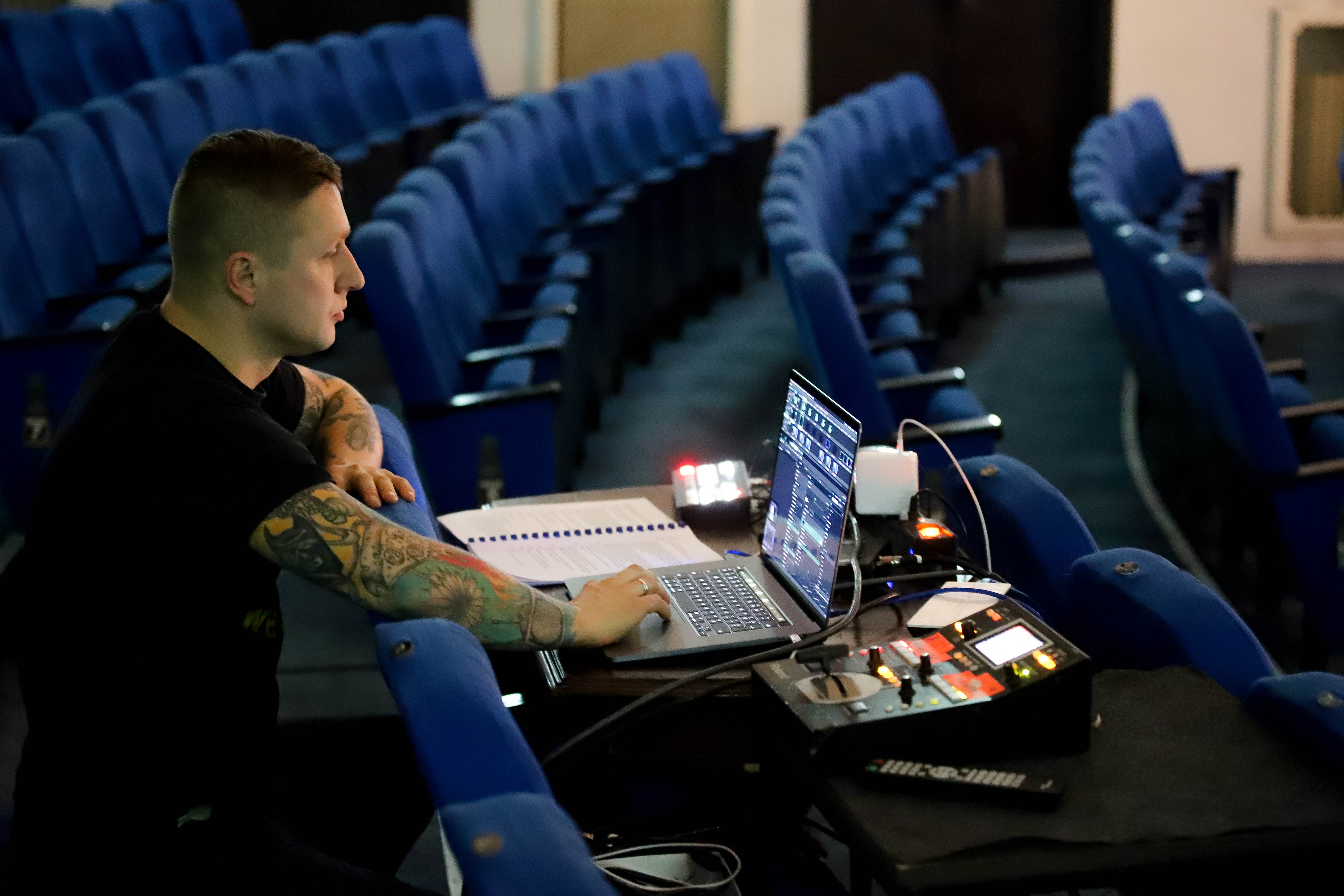 Mężczyzna siedzi przed latopem na teatralnej widowni