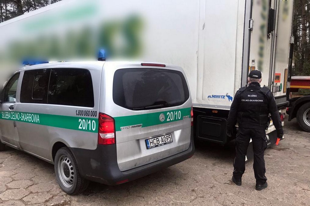Funkcjonariusz KAS stoi przy naczepie tira,w której ukrył się imigrant