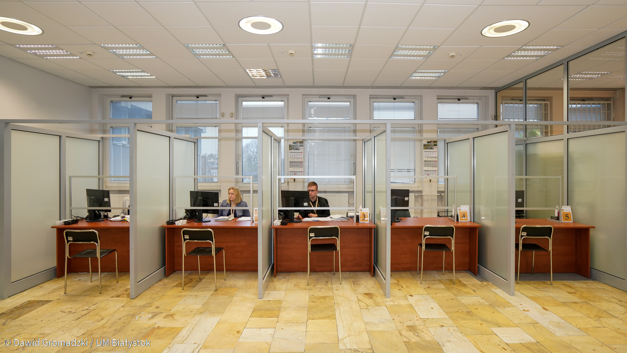 Sala Obsługi Interesantów, na którą składa się pięć stanowisk, oddzielonych od siebie szybą. Przed stanowiskami stoją krzesła, po drugiej stronie, przy komputerze siedzą urzędnicy, za nimi widoczne są duże okna