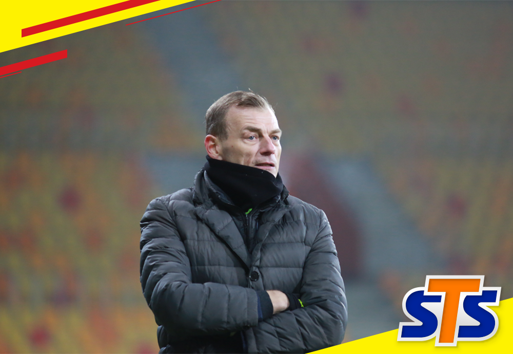 Trener Bogdan Zając stoi na murawie stadionu w Białymstoku. W tle widać puste trybuny.