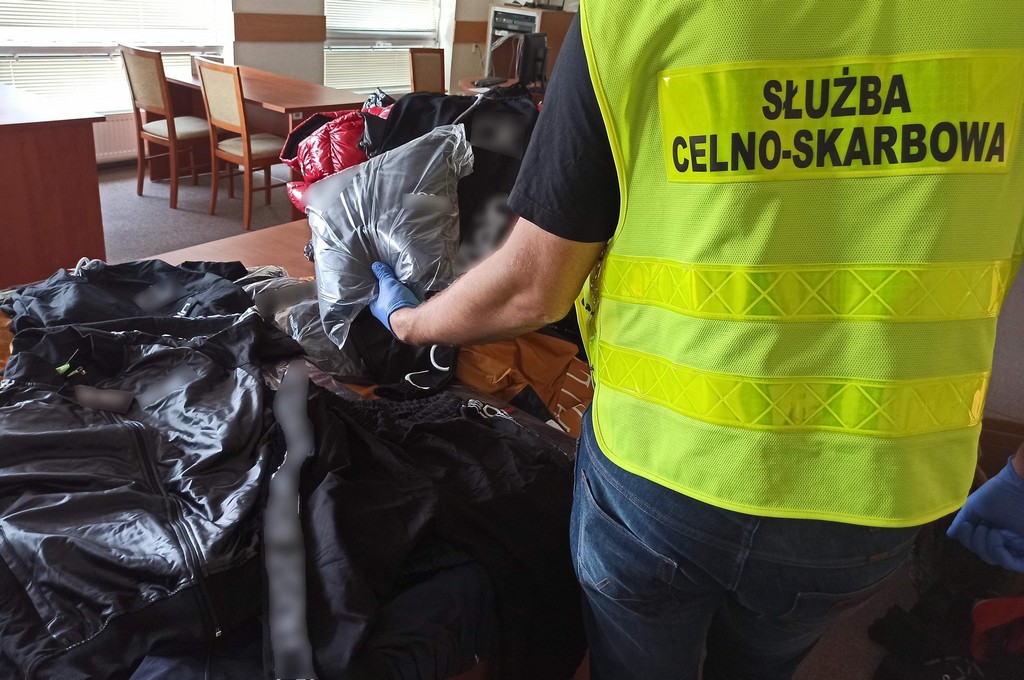 Funkcjonariusz KAS trzyma w ręku podrobioną odzież
