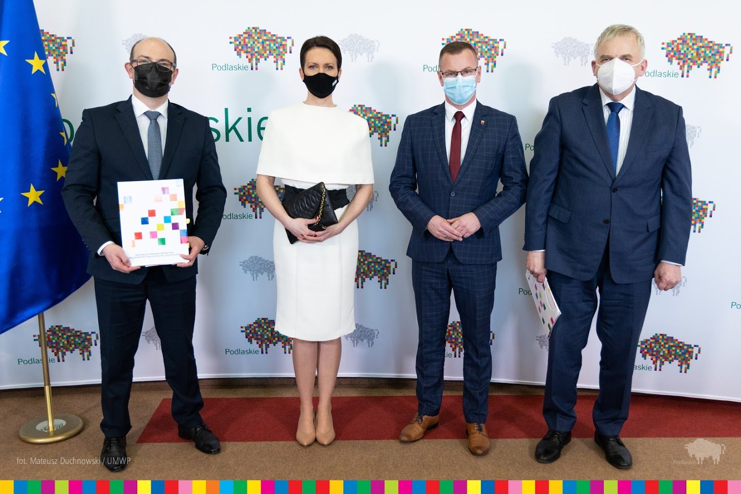 Cztery osoby stoją przed banaerem woj. podlaskiego