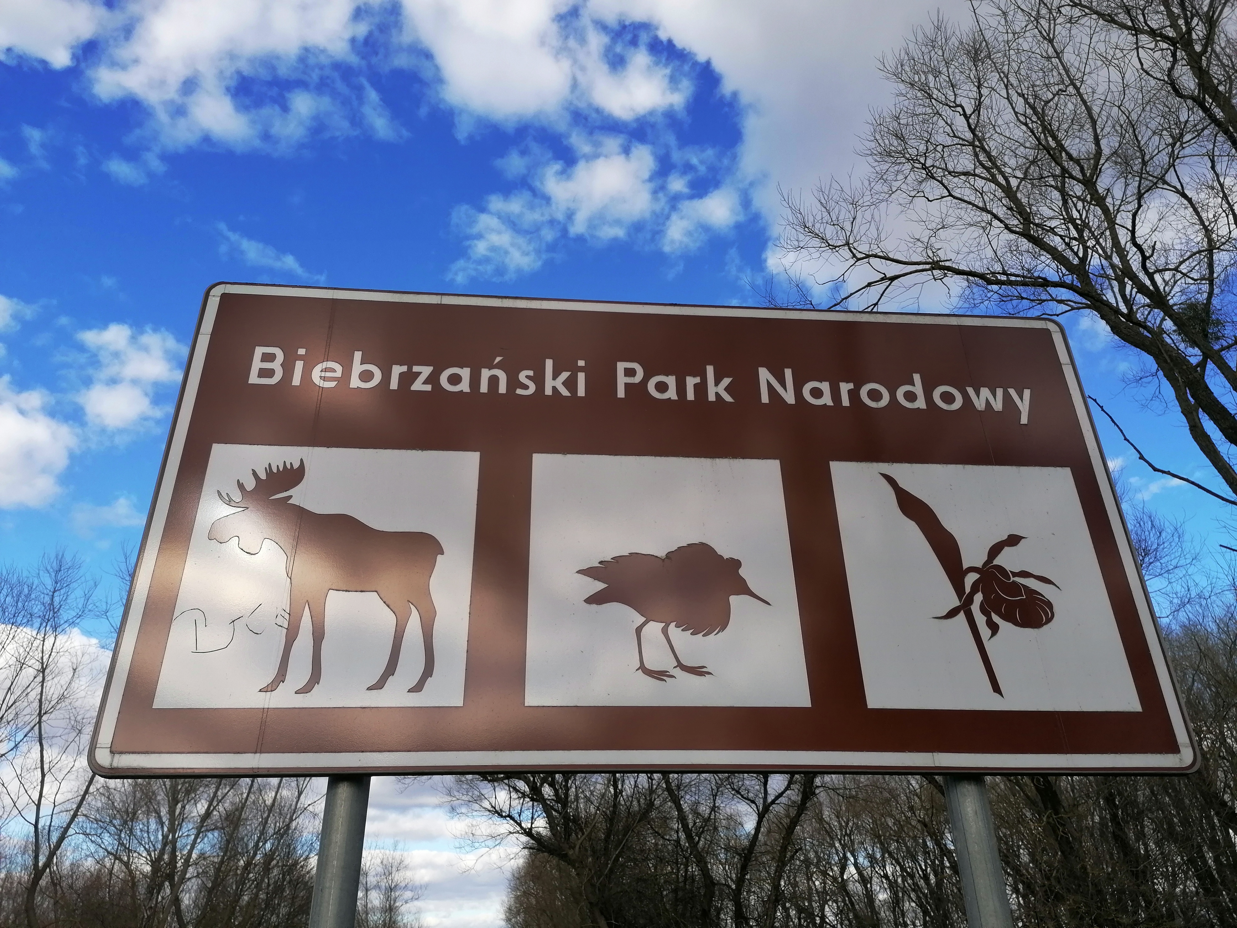 Tablica z napisem: Biebrzański Park Nardowy. Na tablicy widoczny jest łoś, ptak