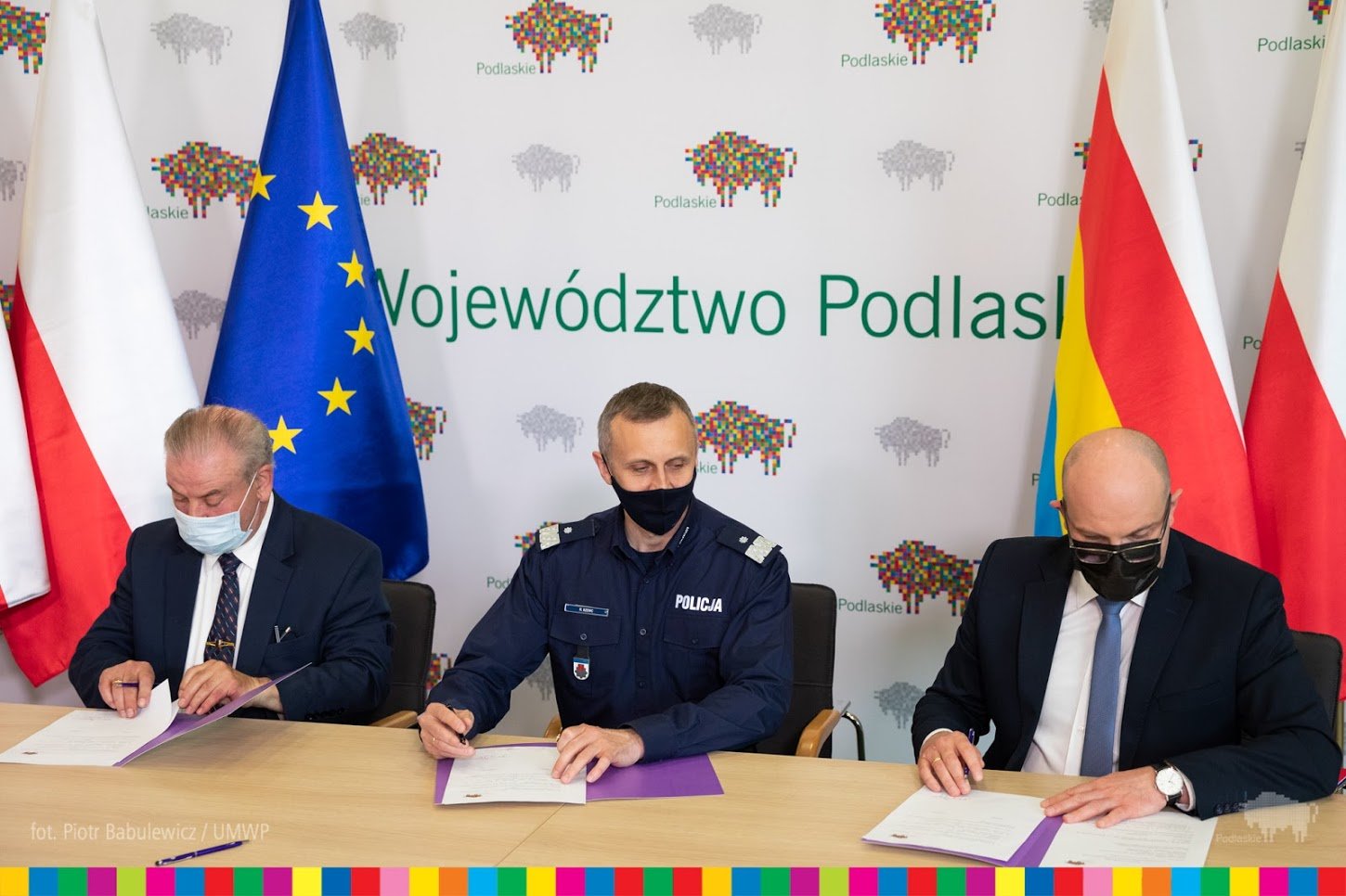 Przy stole konferencyjnym umowę podpisuje trzech mężczyzn