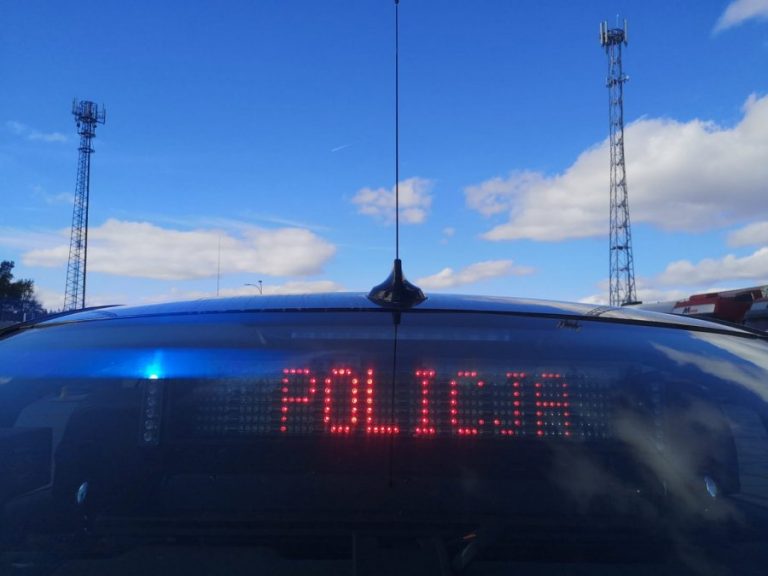 Nieoznakowany radiowóz policji, na tylnej szybie wyświetla się czerwony napis POLICJA