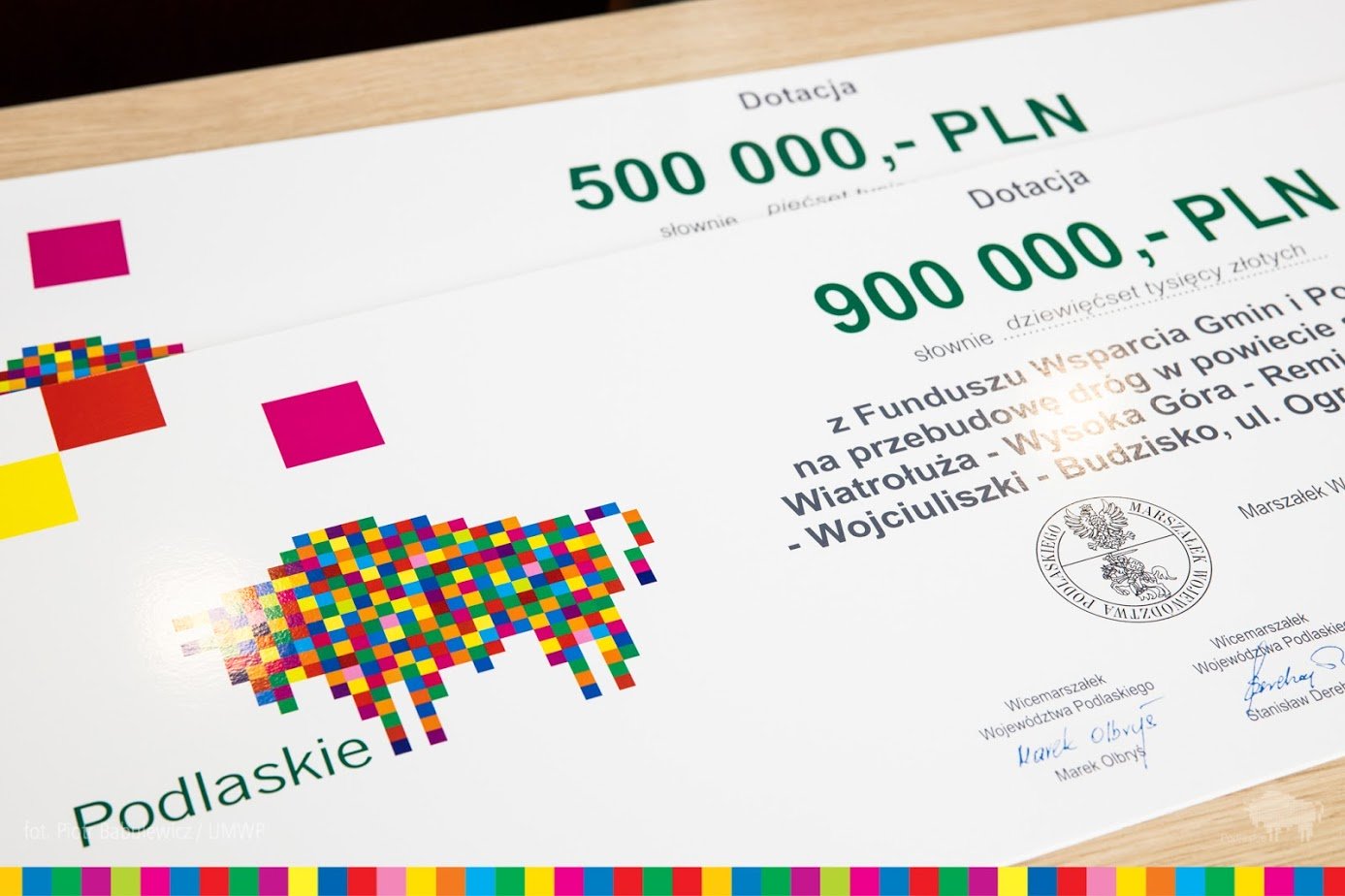 Symboliczne czeki na kwotę 900 tys. złotych i 500 tys. złotych leżą na stole