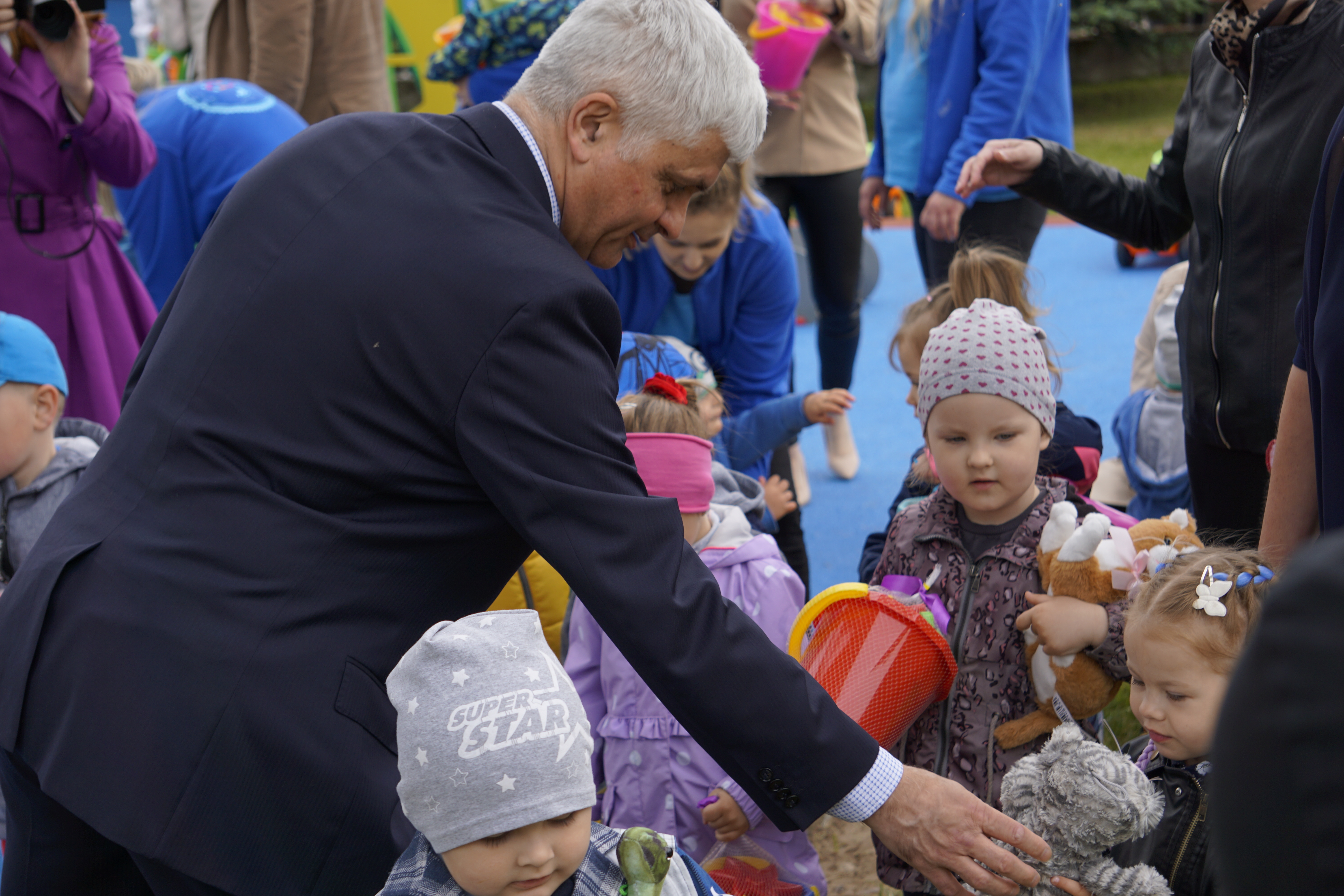 Wojewoda podlaski rozdaje zgromadzonym dzieciom pluszaki