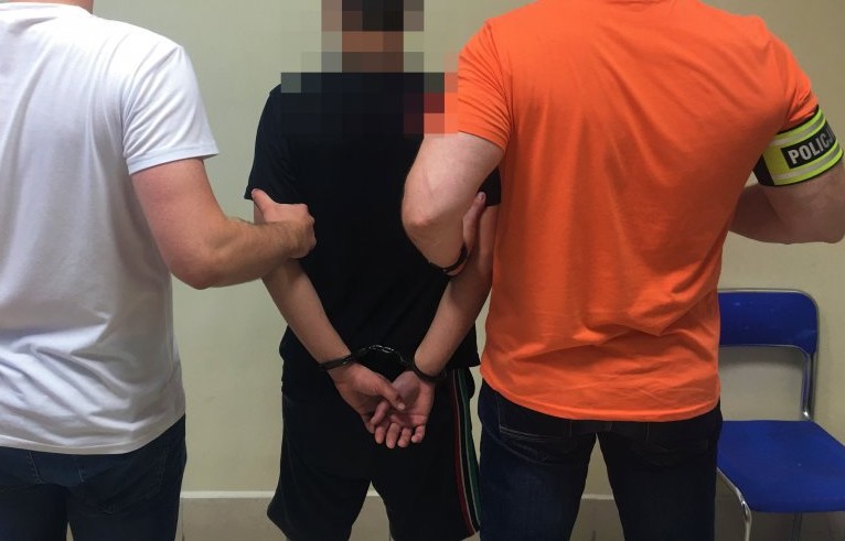 Poiicjanci trzymają pod ręce skutego kajdankami mężczyznę