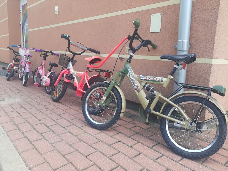 Pięć, kolorowych dziecięcych rowerków stoi opartych o ścianę
