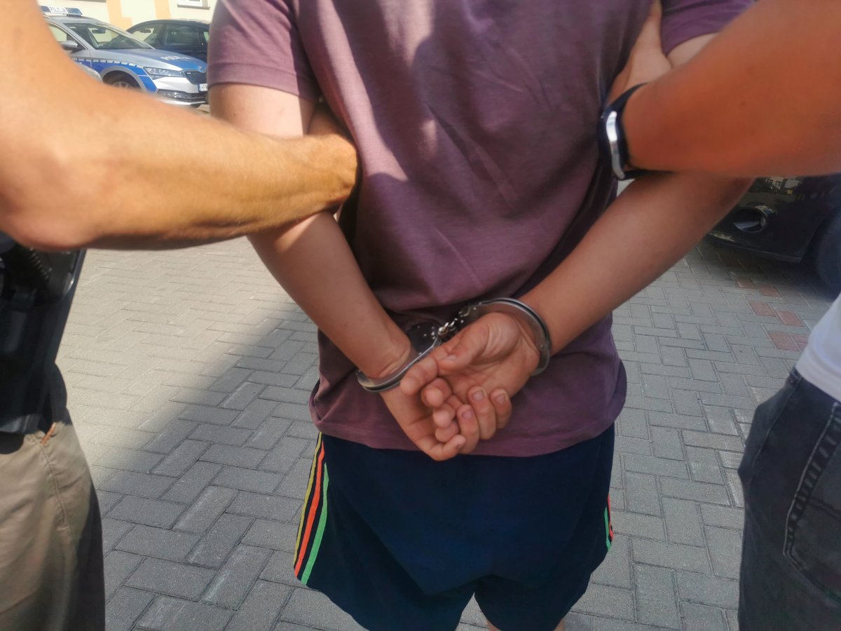 Dwaj policjanci trzymają skutego kajdankami mężczyznę