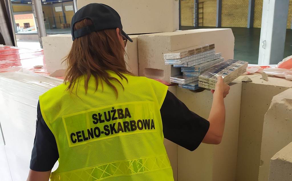 Funkcjonariuszka rozpakowuje papierosy z bloczków betonowych.
