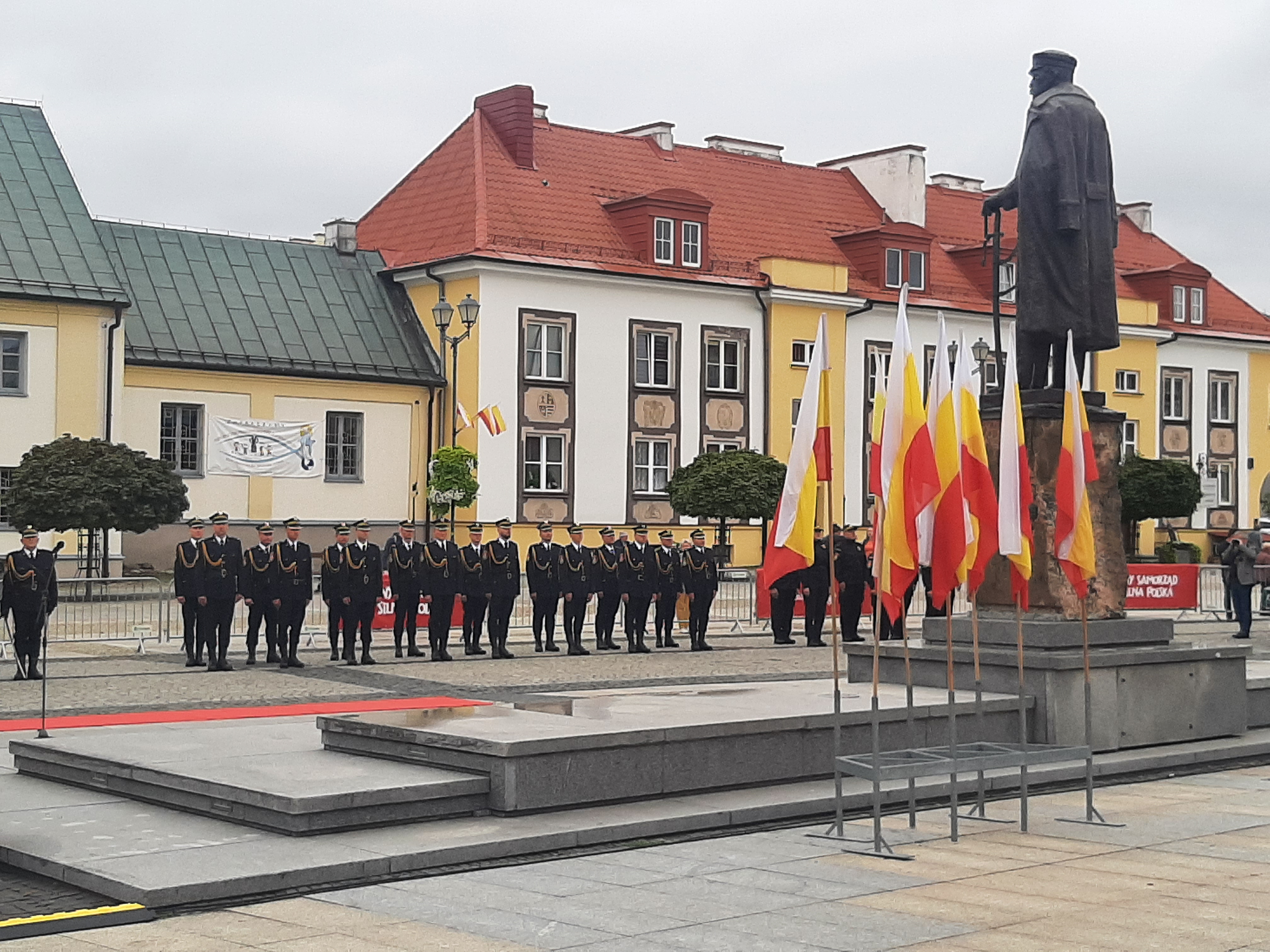 Na Rynku Kościuszki stoi kolumna funkcjonariuszy Straży Miejskiej. Po prawej stronie pomnik Józefa Piłsudskiego