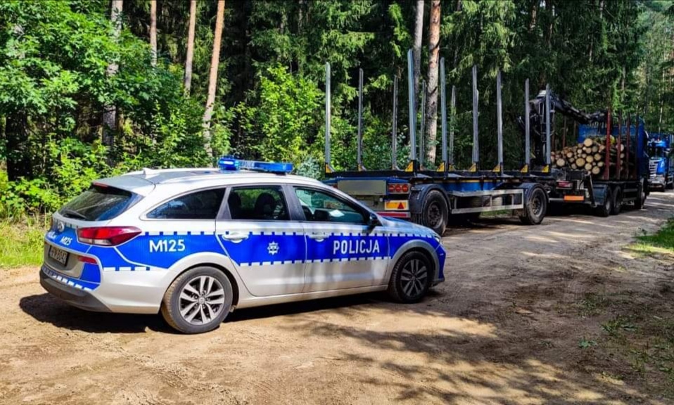 Droga leśna, na której stoi radiowóz policji, scania i motorower