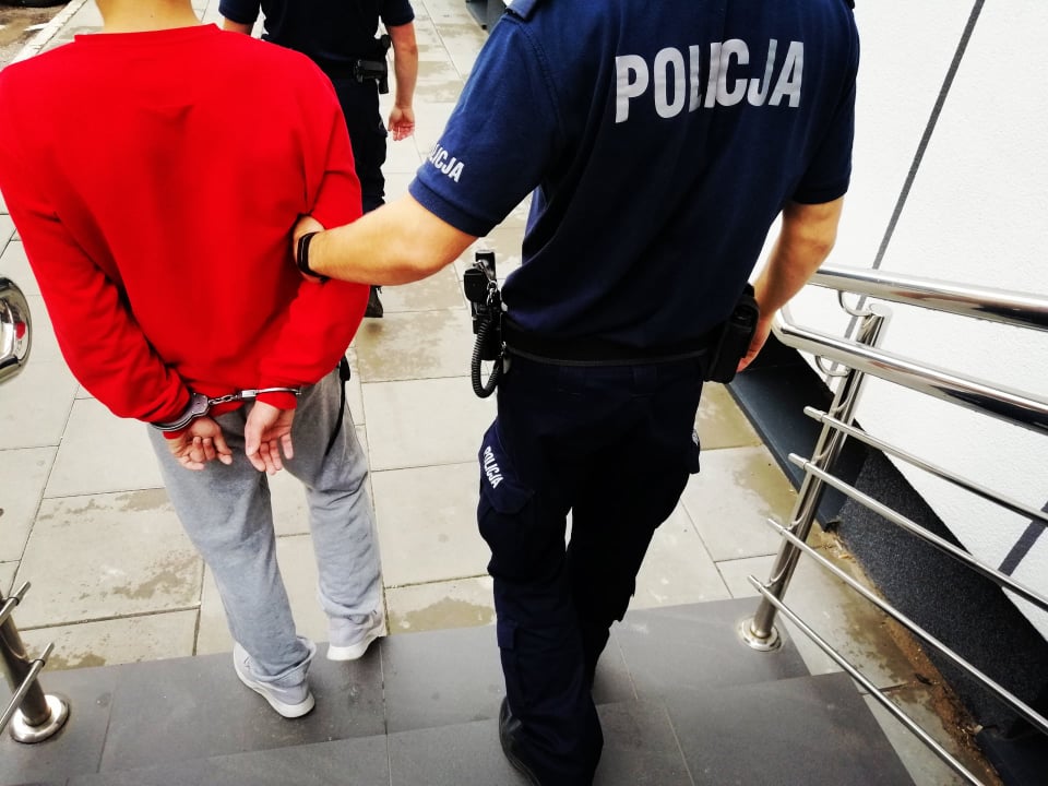 Policjant prowadzi skutego kajdankami mężczyznę