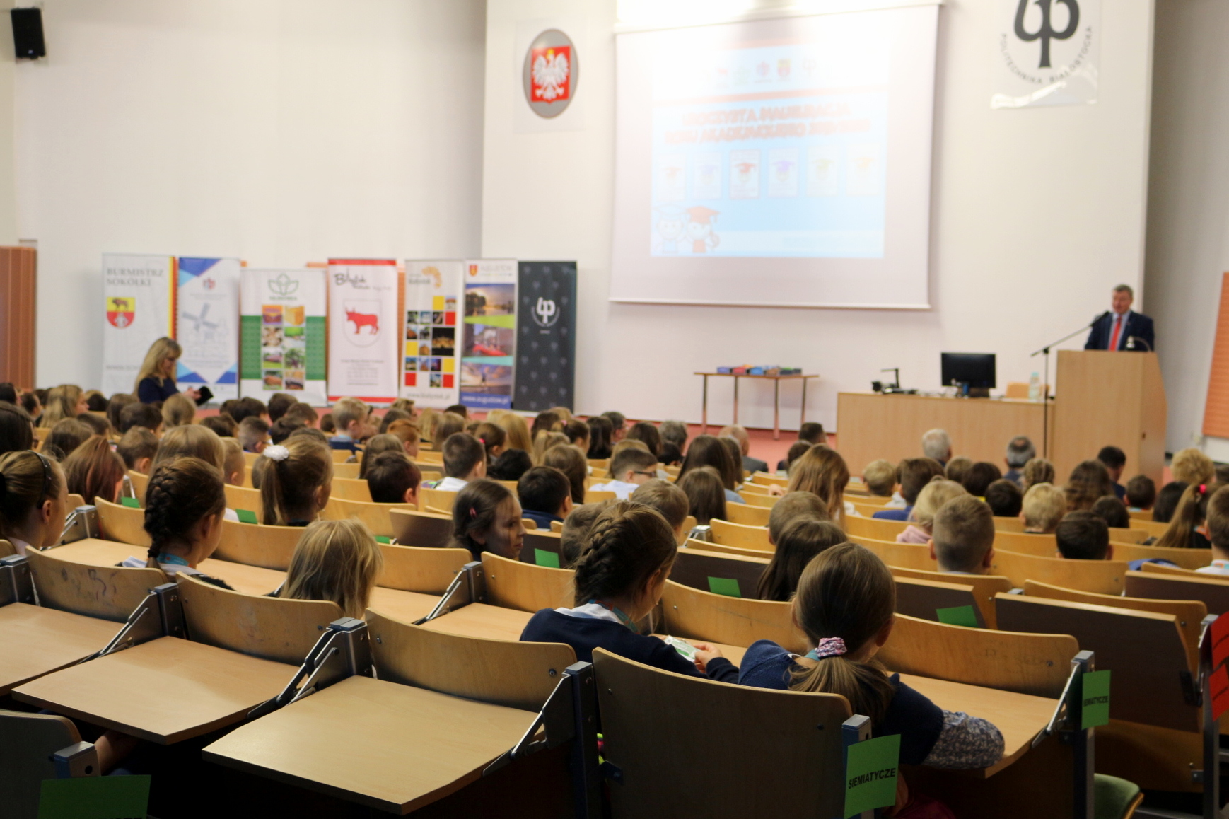 Dzieci siedzą w uczelnianej auli