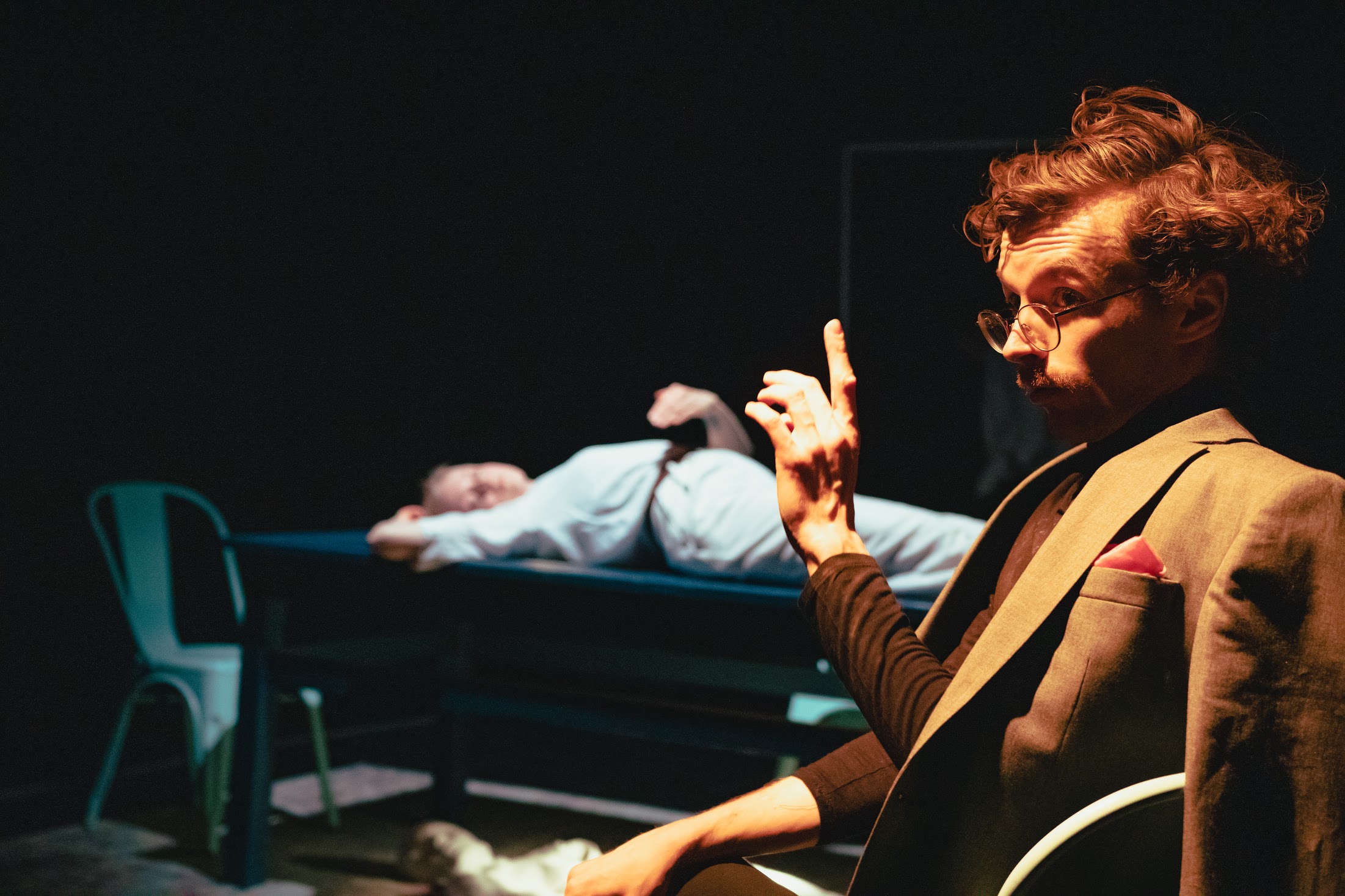 Mężczyzna siedzi na krześle ustawionym na teatralnej scenie