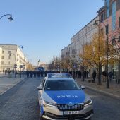 radiowóz na ulicy, w tle tłum policjantów