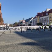 Centrum miasta, w tle widać tłum trzymający transparent o treści rodzina równa się chłopak plus dziewczyna