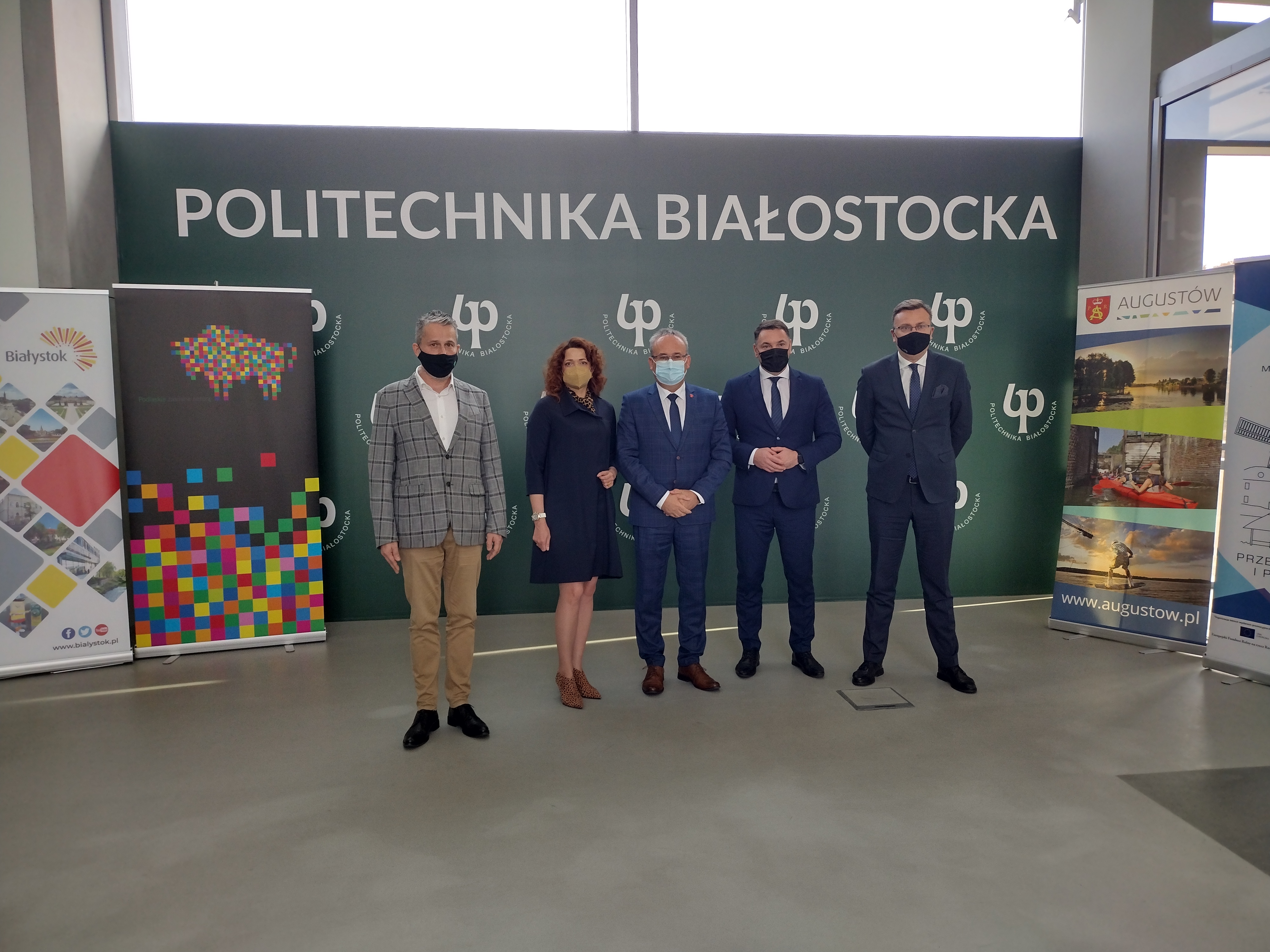 Pięć osób stoi na tle zielonej ścianki z białym napisem Politechnika Białostocka