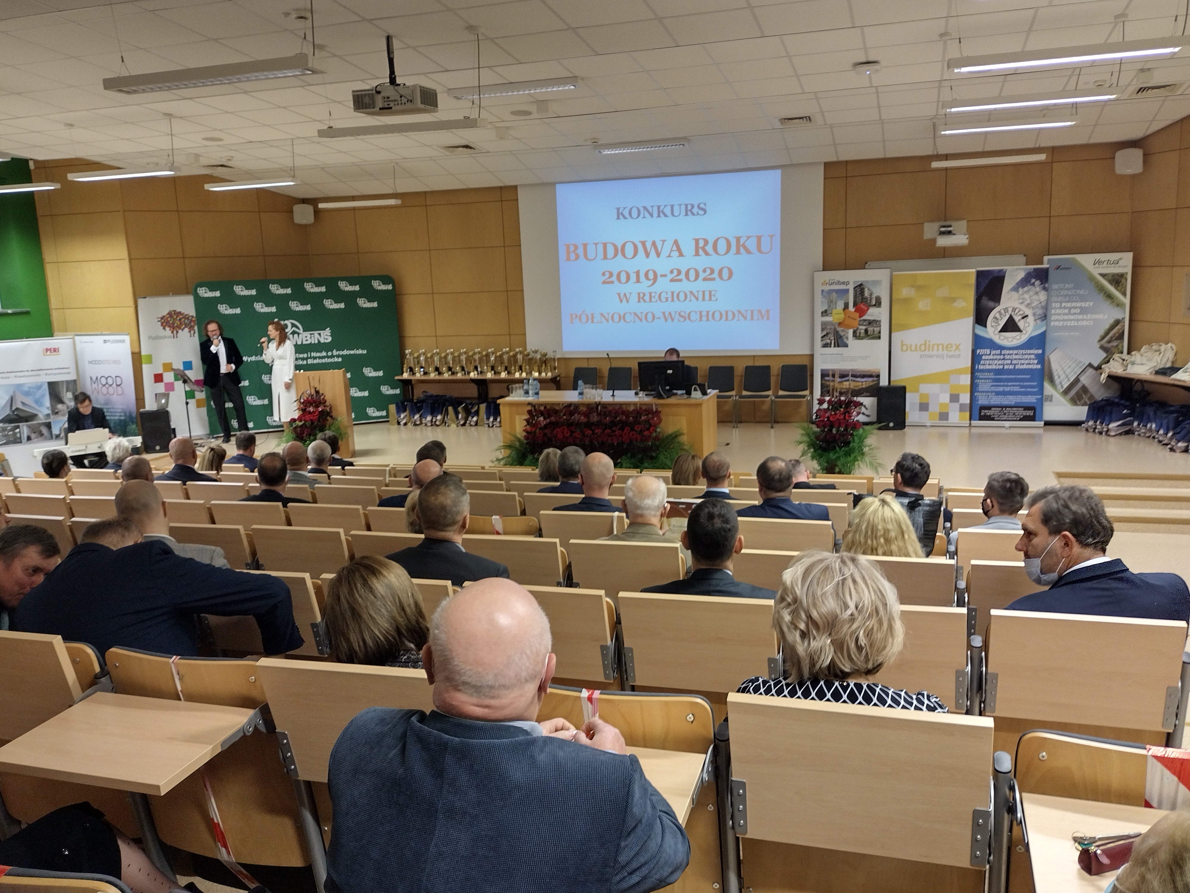 Aula, z fotelami zamontowanymi w rosnących rzędach. Widać ludzi siedzących tyłem. W oddali umieszczony jest rzutnik