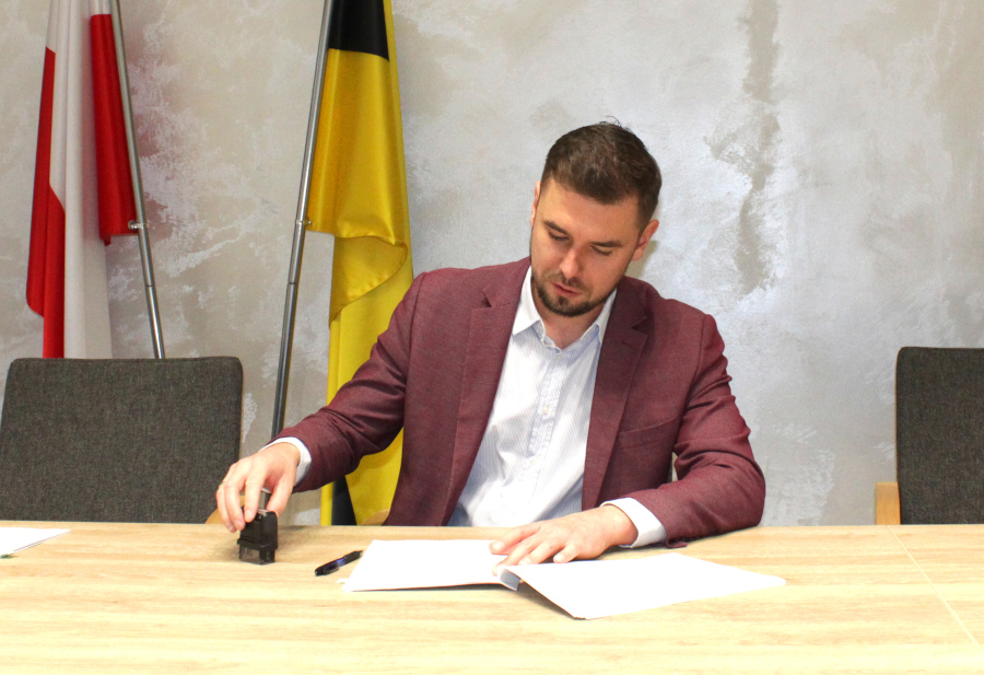 Mężczyzna siedzi przy biurku, stempluje pismo