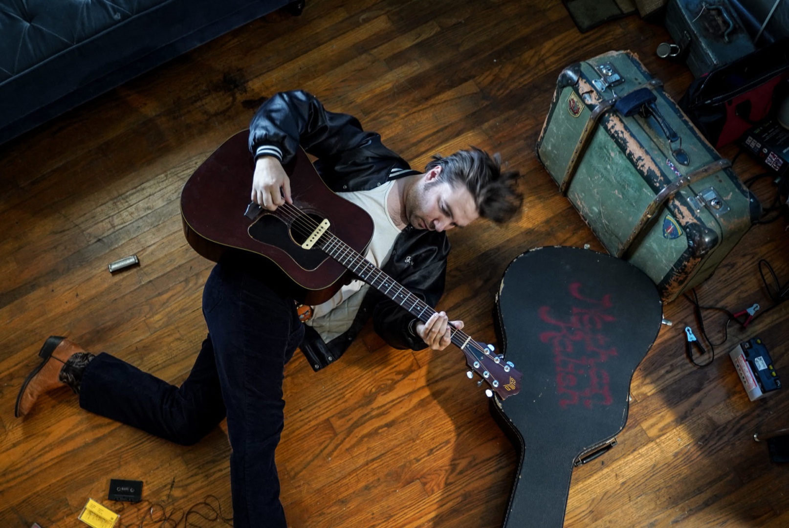 Mężczyzna leży na podłodze, w ręku trzyma gitarę