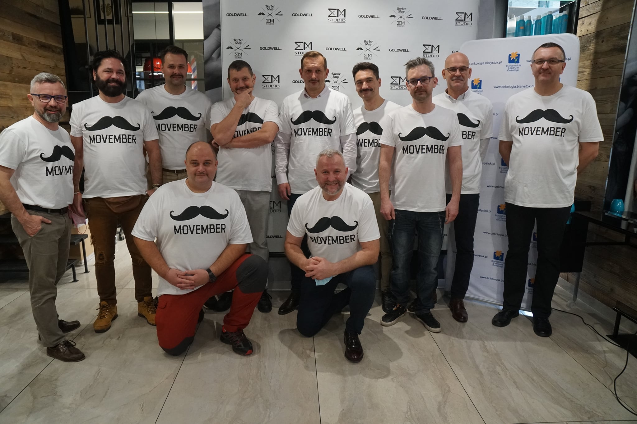 Grupa mężczyzn w białych koszulkach, na których namalowano wąsy i napisano Movember