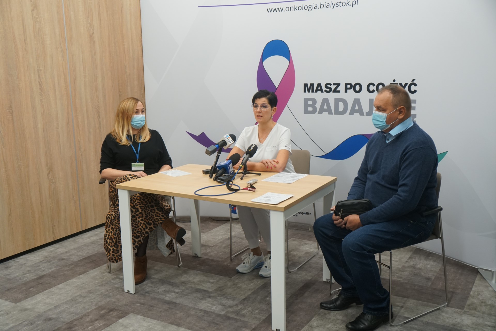 Trzy osoby siedzą przy stoliku w trakcie konferencji prasowej