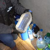 Funkcjonariusz KAS trzyma butelkę z nielegalnym alkoholem
