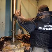 Funkcjonariusz KAS przy aparaturze do produkcji bimbru